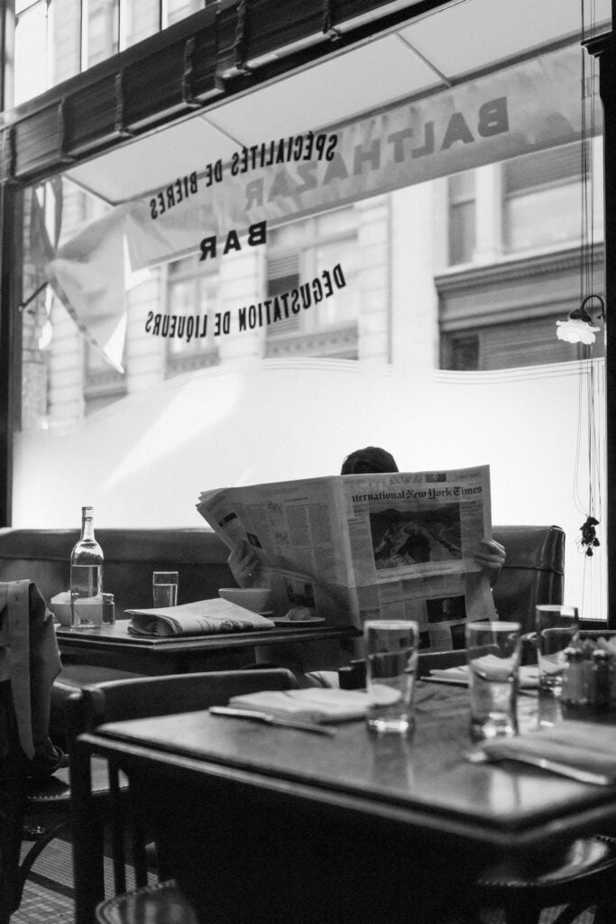 En man sitter i en restaurang och l&auml;ser en nyhetstidning.